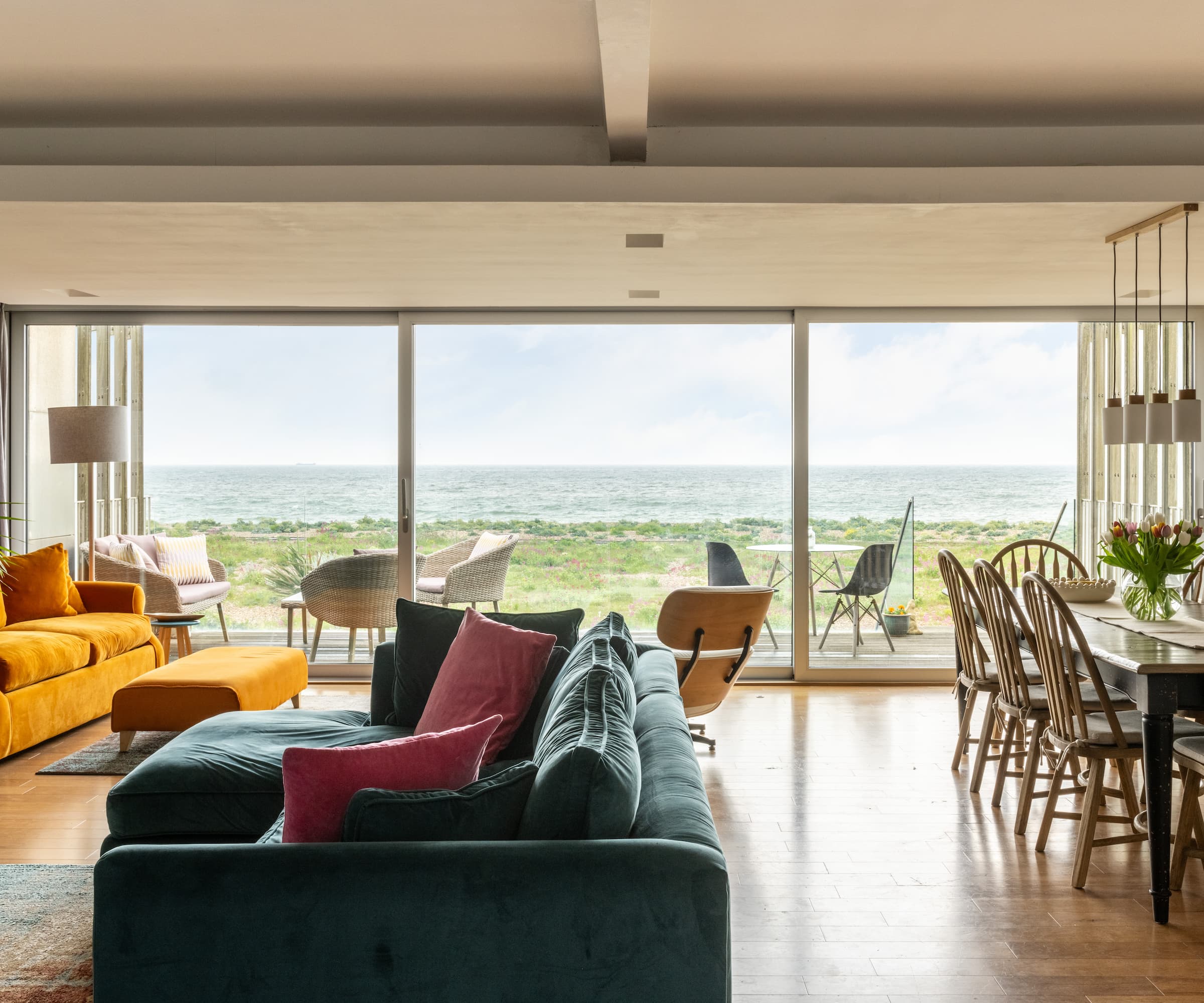 An open plan living room with a bifold door leading to a balcony with a view of the sea