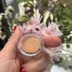 a hand holding a pot of nars concealer