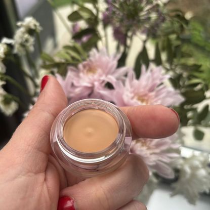 a hand holding a pot of nars concealer
