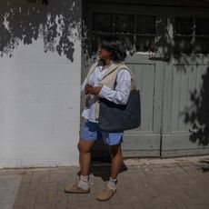 London woman wears boxer shorts, white button up, oversize bag and Birkenstock Arizona Clogs.