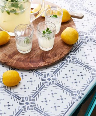 Lazy susan with jug, glasses and lemons on patterned table top