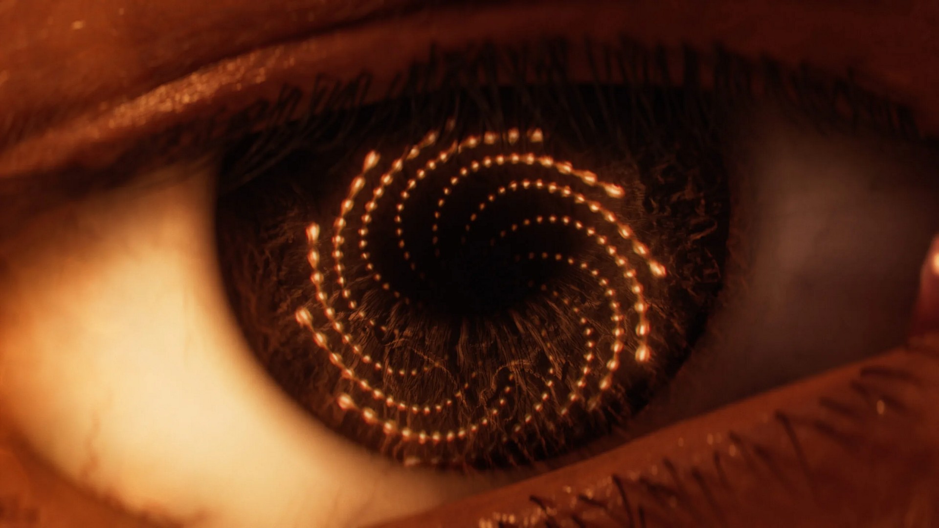 A close-up or Arjun Devraj's eye shows spirals of yellow circles reflected in it, in a Saros cutscene