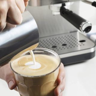 Milk being poured into a cup filled with coffee