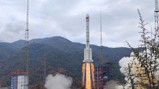 A Chinese Long March 3B rocket launching with mountains in the background.