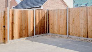 New wooden fence with concrete posts and paved garden