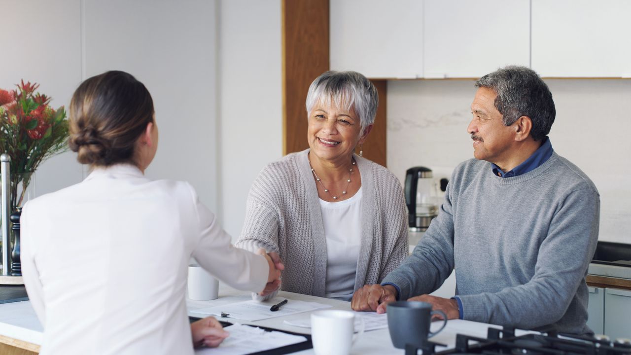 A lawyer meets with an older couple in her office.