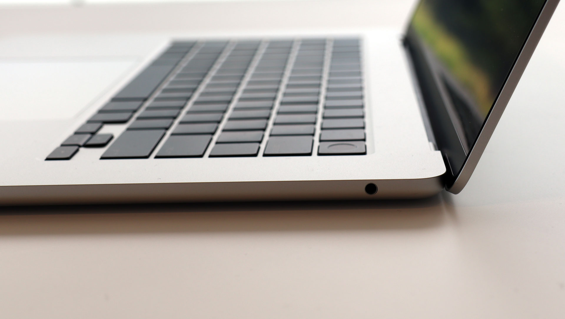En åpen 15-tommers MacBook Air på et lyst bord med grønne omgivelser.