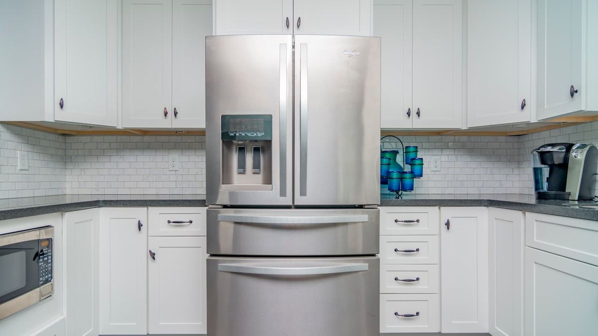 A white kitchen and grey fridge in a modern middle class house 