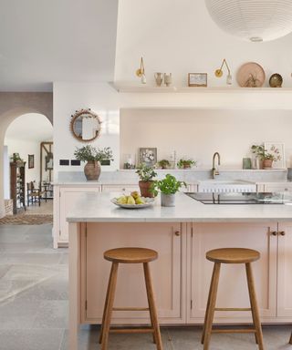 Pink kitchen island with marble countertops and a cooktop