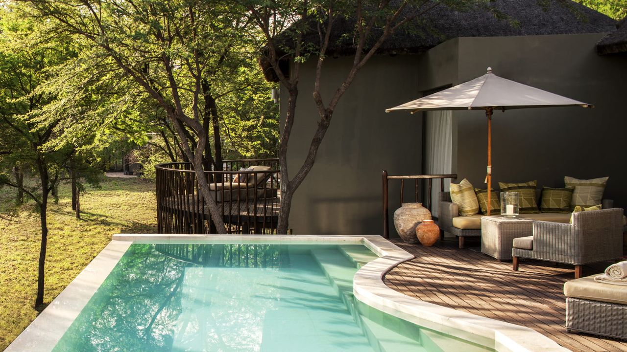 Image of a pool deck with a small pool that is outdoor to a grassy area.
