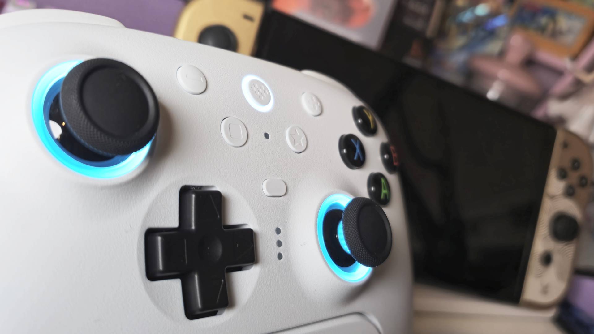 Close up of the white SKU 8BitDo Ultimate 2 Wireless controller taken by writer Rosalie Newcombe, with a blurred OLED Switch behind it.