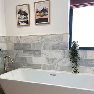 bathroom with white and grey tiles wall bathtub and frames on wall