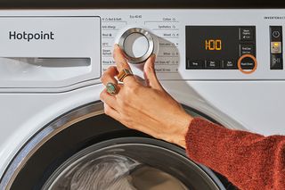A woman selecting the Rapid / Green feature on a Hotpoint washing machine