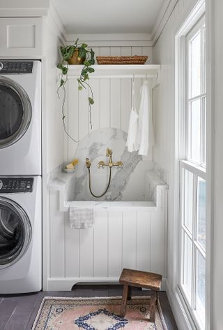 white laundry room with marble sink, washers, shiplap