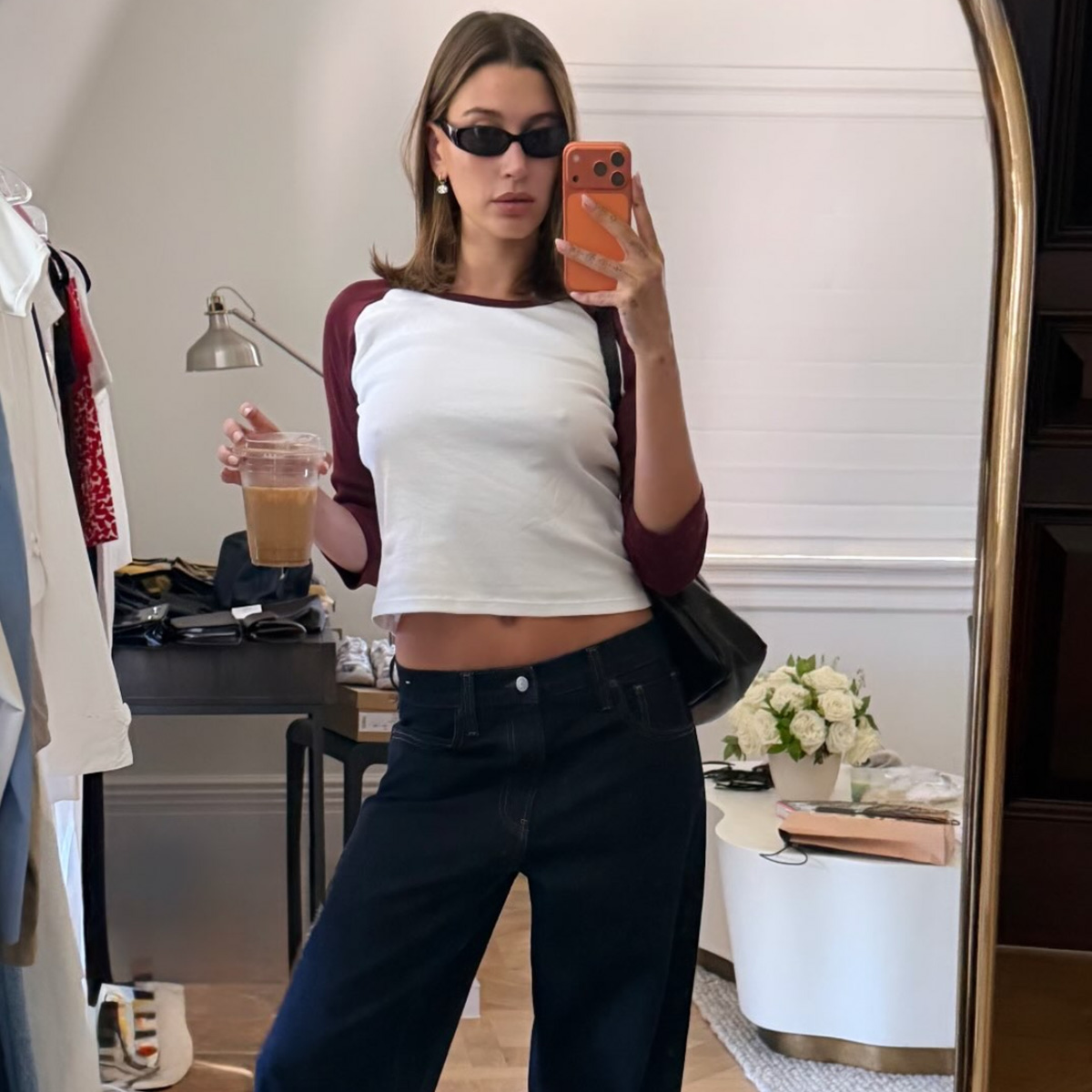 Hailey Bieber wearing a baseball tee with low-rise dark-wash jeans and cone-heel thong sandals.