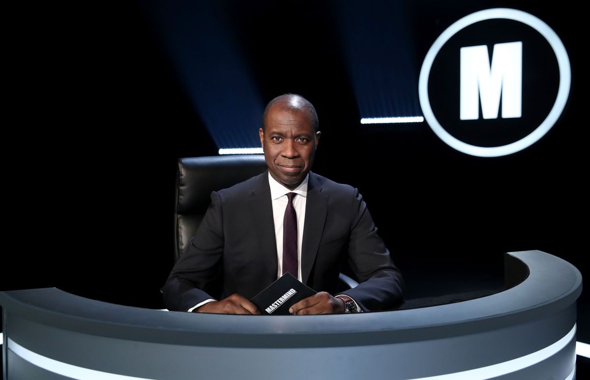 Clive Myrie sitting behind the host&#039;s desk in the Mastermind studio