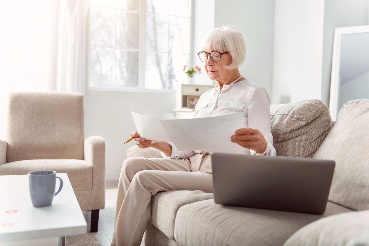 Elderly lady comparing charts on printouts.