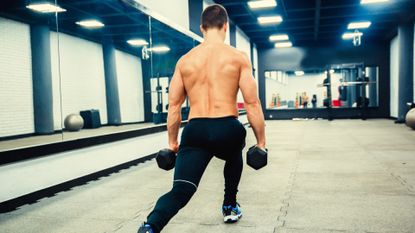 A topless man doing dumbbell lunges