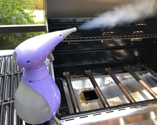 A steam cleaner being used to clean BBQ grill grates