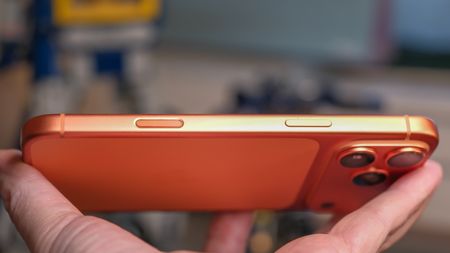 Camera Control button software features on the Apple iPhone 17 Pro Max in Cosmic Orange color, showing zoom, switching cameras, Magnifier app, and more
