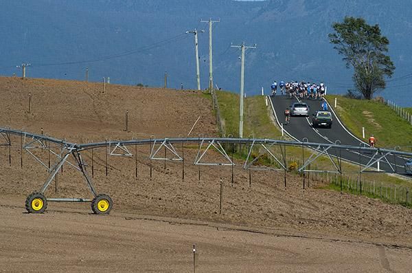 Riders head over a rise alongside irrigation machinery near Cressy.