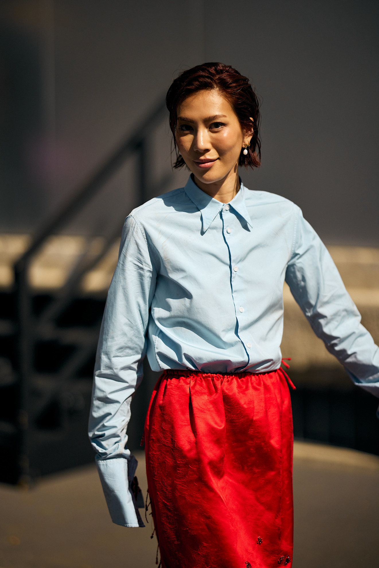 an asian woman with a short red bob in a red skirt and blue shirt