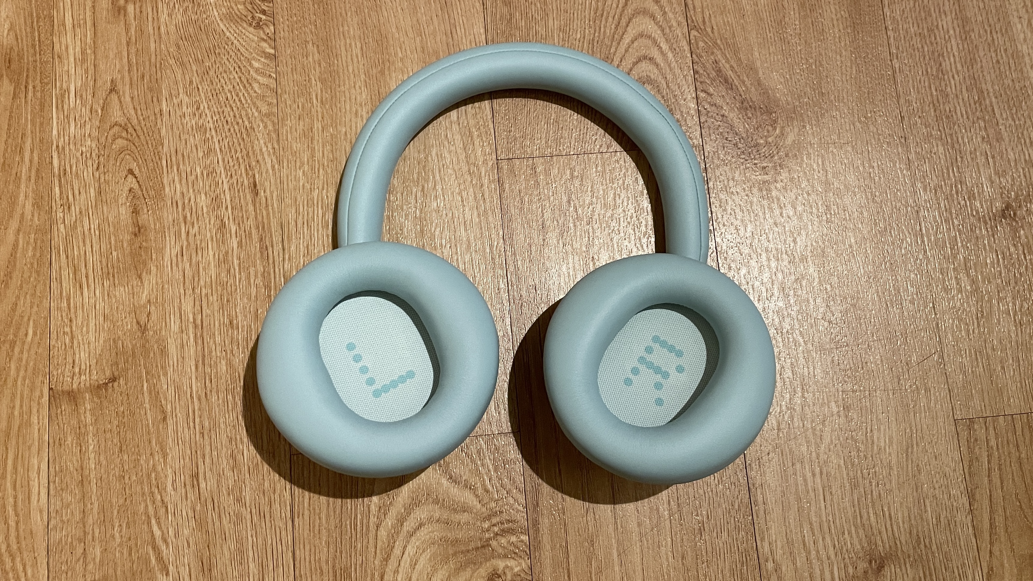 CMF Headphone Pro in pistachio green held in a hand or hung on a barbell, being pushed up by a carved frog