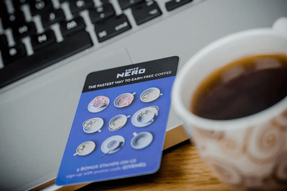 a caff&eacute; nero loyalty card on a laptop next to a cup of coffee