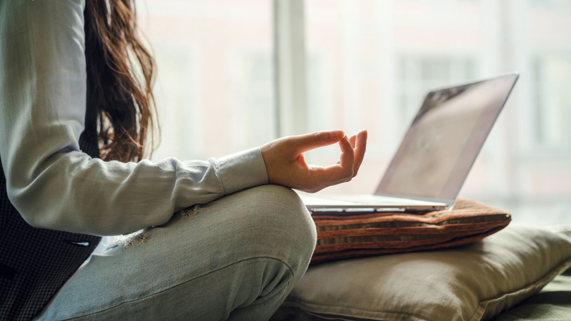 A woman practising mindfulness crossed legged in front of her laptop after a sleepless night