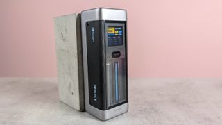 Cuktech 20 Power Bank leaning on plinth, on desk with pink background