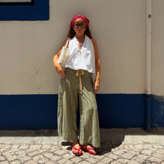 Influencer Rebecca Ferraz Wyatt wearing striped linen trousers with a white halterneck top and red flip flops. 