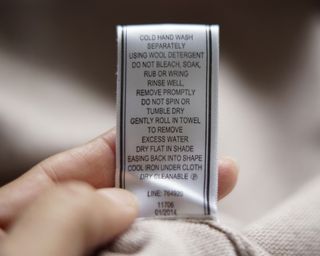 how to load a washing machine - a care label on a piece of clothing - GettyImages-559443839