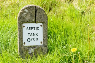 A concrete marker sticking out of a grass lawn saying septic tank