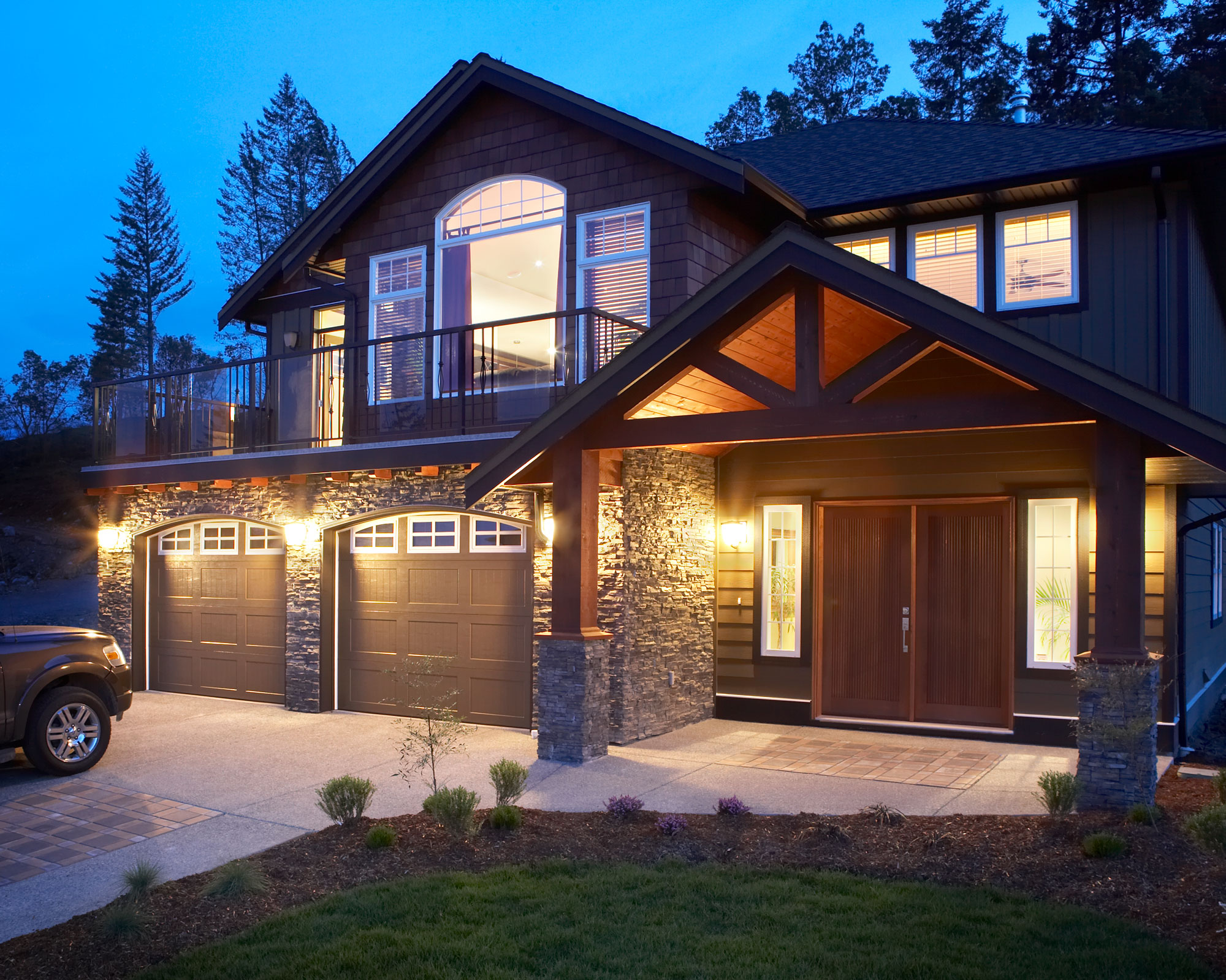 large house with outdoor lighting and two garages