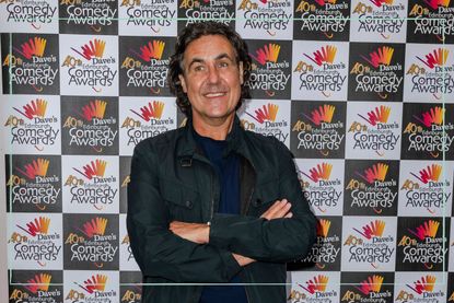 a medium shot of comedian Micky Flanagan posing with his arms crossed at a Dave promotional event