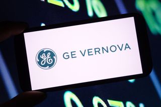 GE Vernova logo on smartphone with ticker board in the background