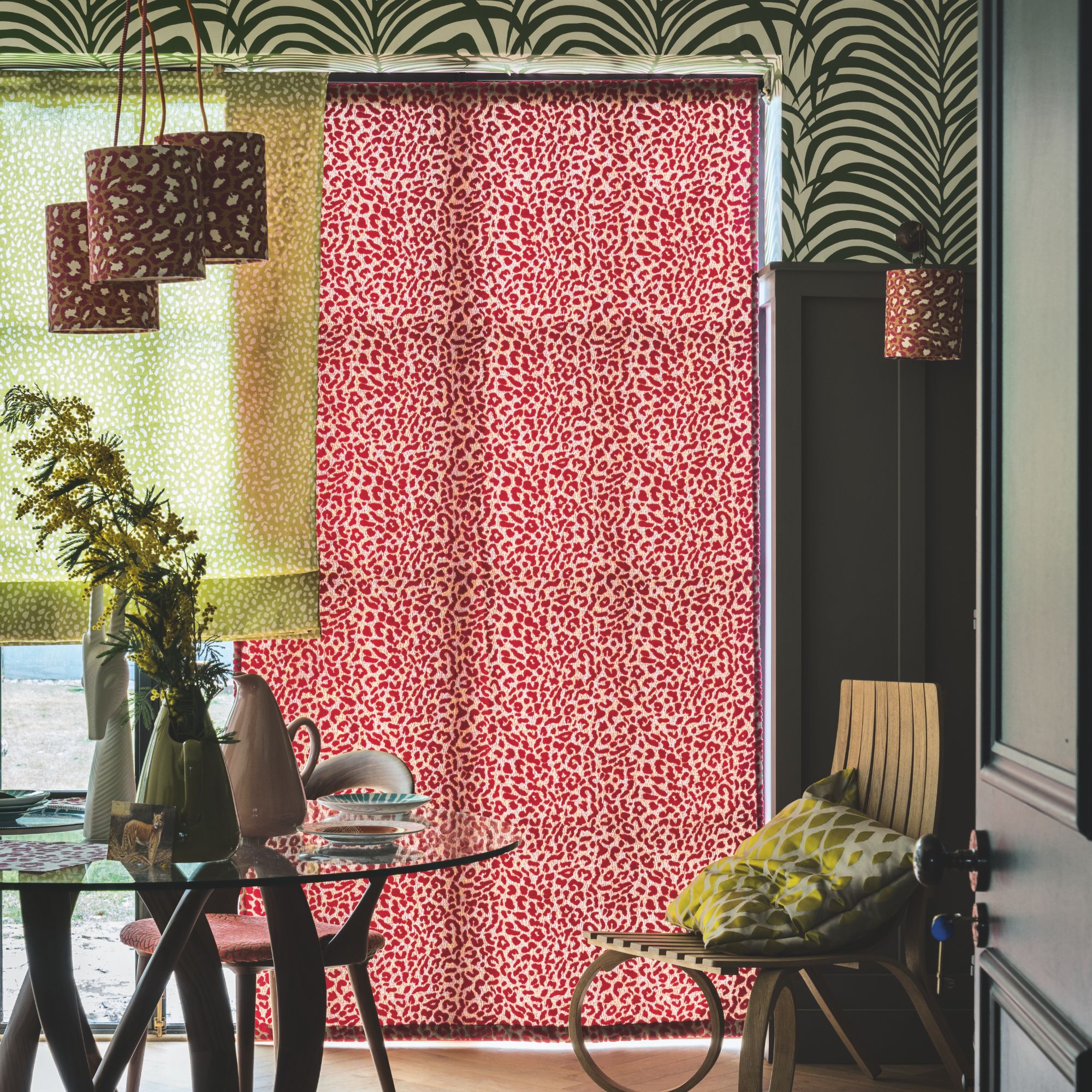 A large window with a sheer animal print closed curtain