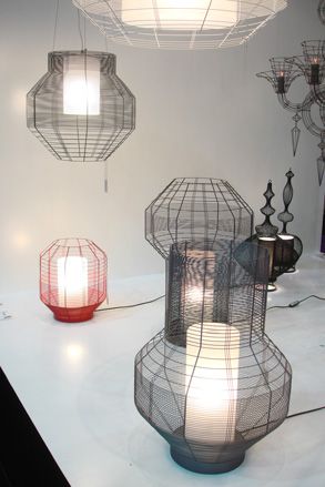 Multiple wire-framed multi-sided candle holders on a table and hanging from above.