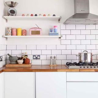 kitchen room with wooden worktop and wall shelves with metro tiles