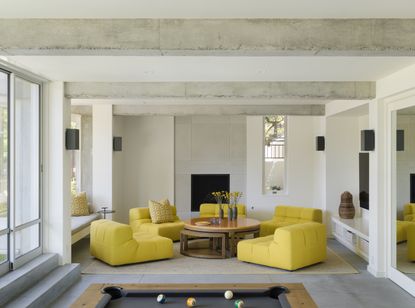 Off-white walls, bright yellow armchairs and exposed concrete beams