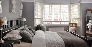 grey bedroom with white blinds covering the bay window