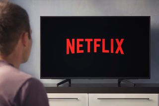 Someone slightly off camera is looking at the Netflix logo on a TV