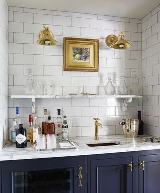 A kitchen lighting idea with brass wall sconces used to light a bar alcove