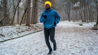 man running through a snowy woodland