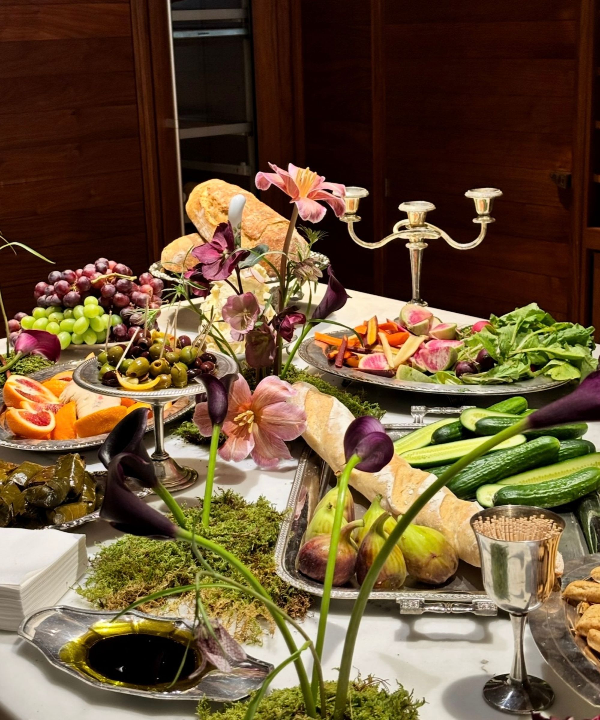 Table set with fruit, salad and bread on silver trays and candlesticks