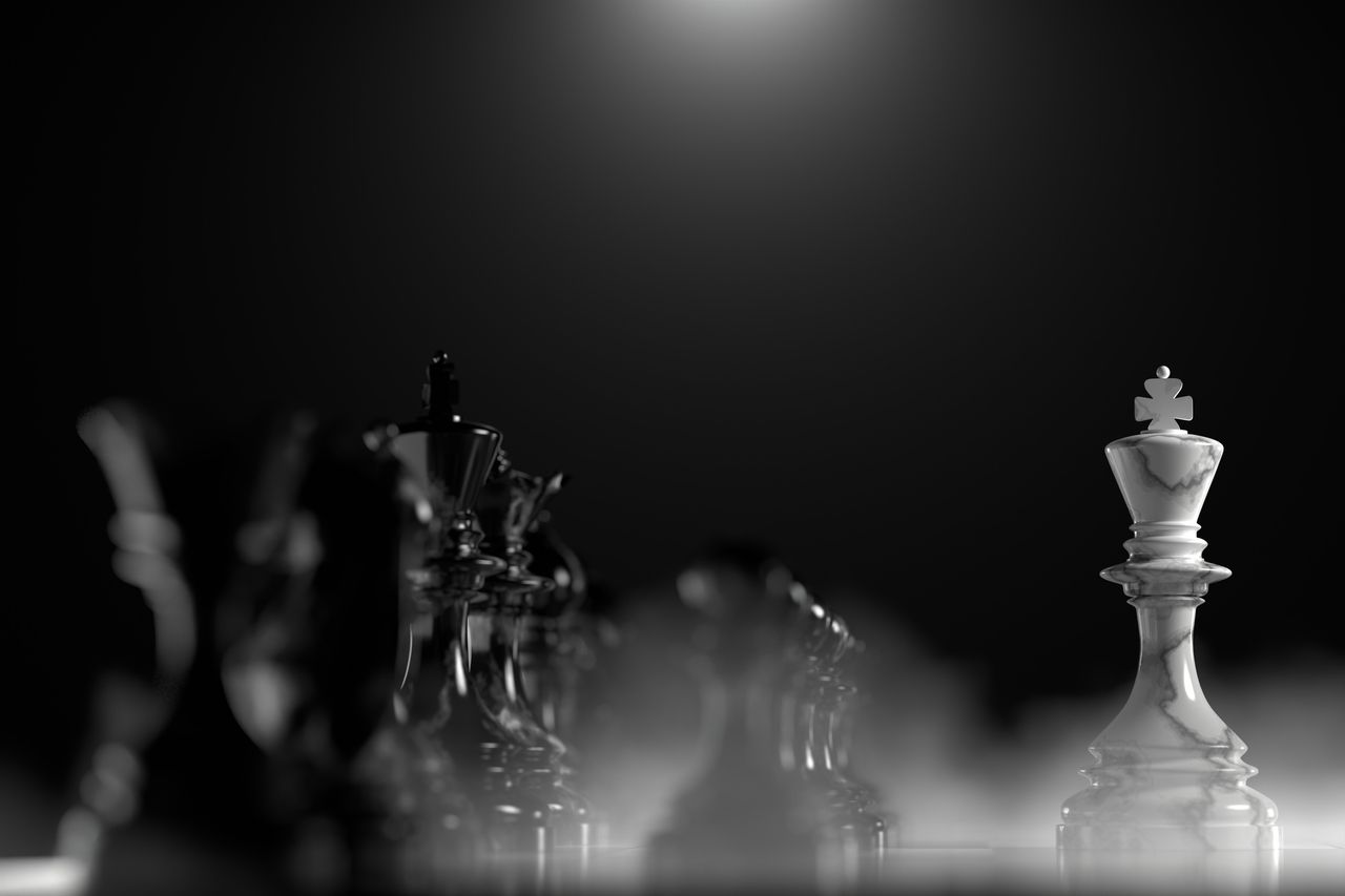 A white marble king on chess board facing the whole black chess army, representing defensive stocks.