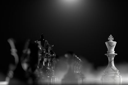 A white marble king on chess board facing the whole black chess army, representing defensive stocks.