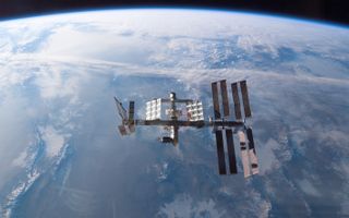 international space station backdropped by earth, in sunlight