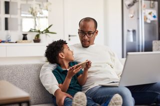 father sat with son on phone and laptop