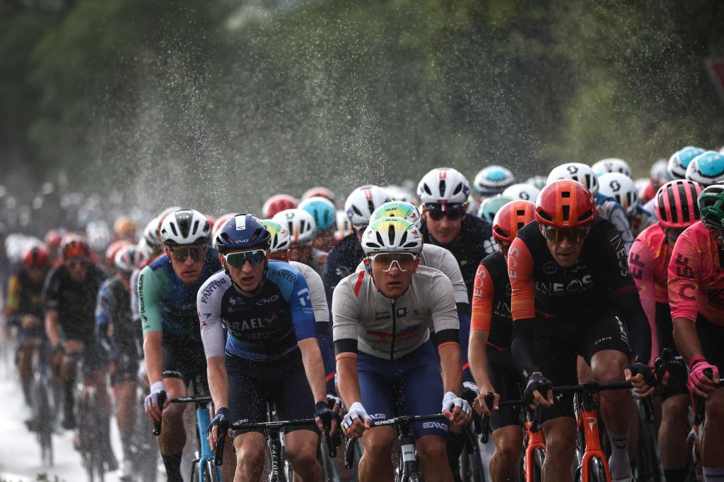 The pack of riders (peloton) kick up spray as they cycle in the rain during the 8th stage of the 111th edition of the Tour de France cycling race, 183,5 km between Semur-en-Auxois and Colombey-les-deux-Eglises, on July 6, 2024. (Photo by Anne-Christine POUJOULAT / AFP)